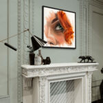 Vue large d'un salon chic avec moulures, montrant le portrait "Eye Scarlett" au-dessus de la cheminée, accompagné d'un grand lampadaire design et d'objets d'art.