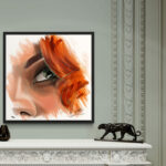 Tableau "Eye Scarlett" encadré en caisse américaine noire, posé sur une cheminée en marbre blanc avec décoration classique et statuette panthère.