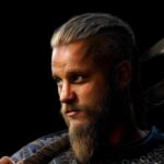 Peinture numérique réaliste de Ragnar Lothbrok de la série Vikings, regard intense et hache sur l'épaule, sur fond noir. Impression d'art Dibon mat.