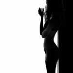 Peinture numérique en noir et blanc montrant la silhouette d'une femme de profil tenant une tasse, se découpant devant une fenêtre lumineuse.