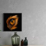 Tableau 'Eye fox' avec cadre noir en caisse américaine, accroché sur un mur gris texturé à côté d'une plante.