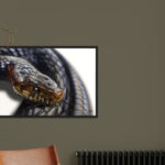 Tableau d'art grand format représentant un serpent noir enroulé, accroché sur un mur gris foncé au-dessus d'un fauteuil en cuir.